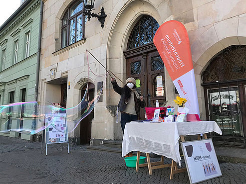 Ute Jaross macht vor dem Rathaus Friedrichshagen eine große Seifenblase