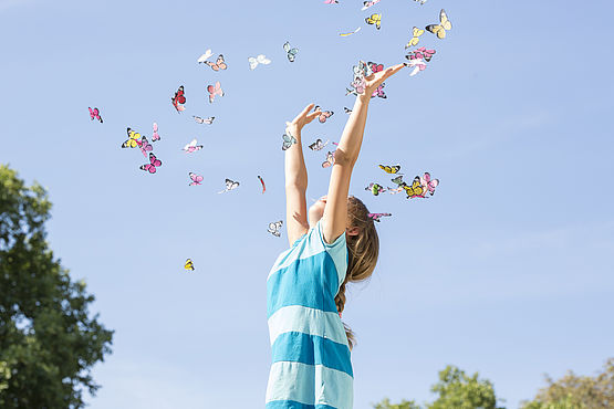 Kind wirft Schmetterlinge in die Luft