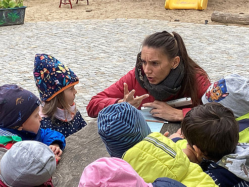 Eine Erzieherin spricht mit Kita-Kindern