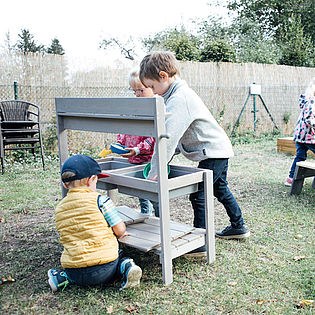 Kinder decken den Tisch auf dem Spielplatz