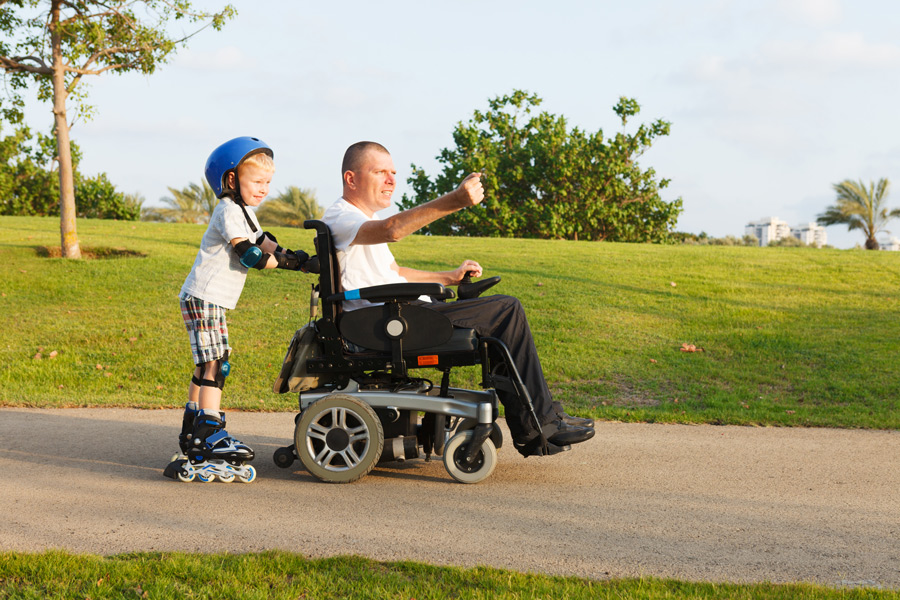 Kind auf Rollschuhen, Mann auf fahrbarem Rollstuhl