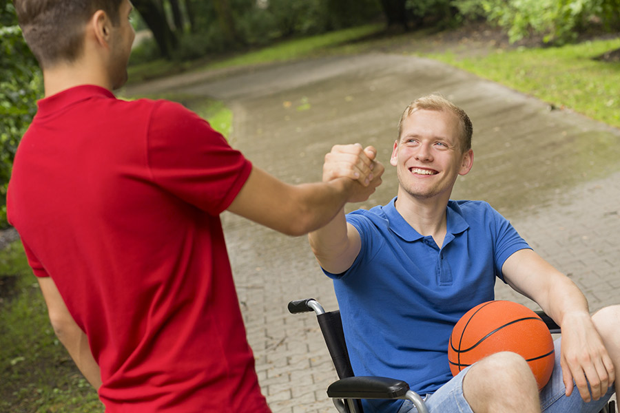 Ein Mann und ein Mann im Rollstuhl geben sich die Hand
