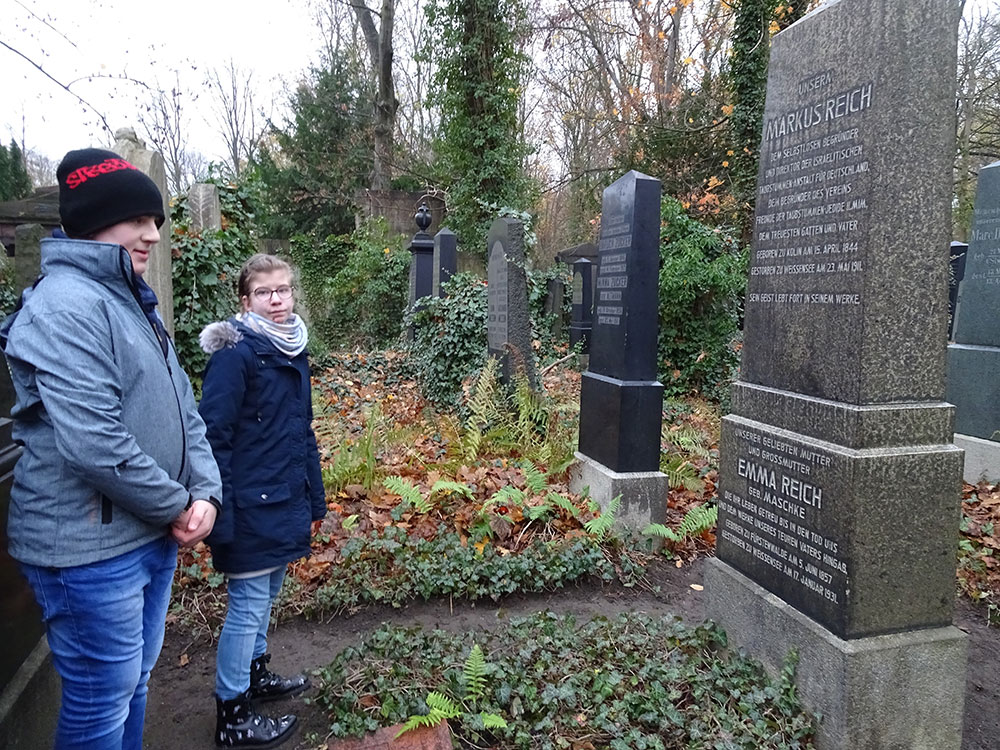 Zwei Kinder stehen vor dem Grabstein von Markus Reich