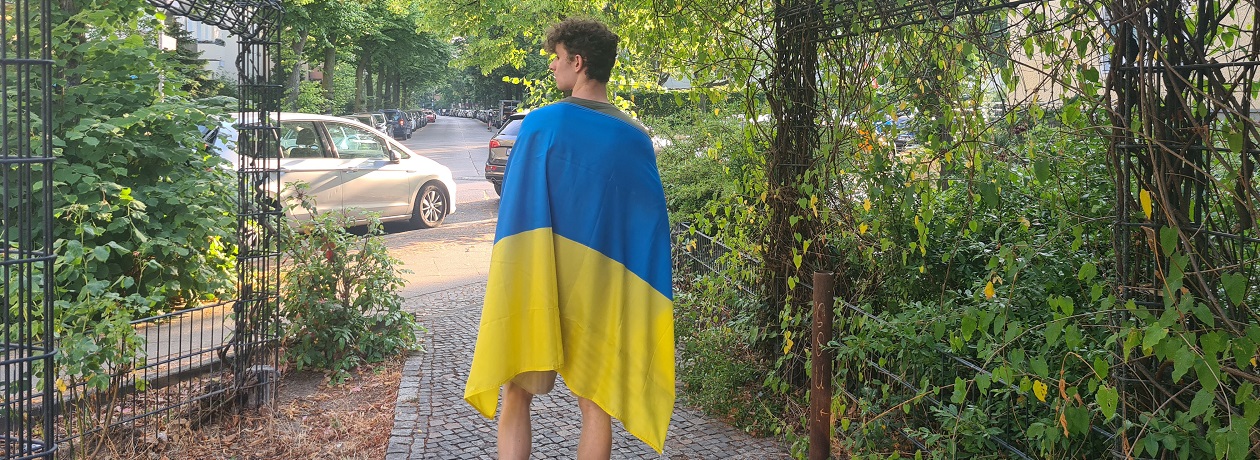 Ein junger Mann mit einer großen ukrainischer Flage auf dem Rücken