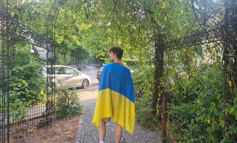 Ein junger Mann mit Ukraineflage auf dem Rücken