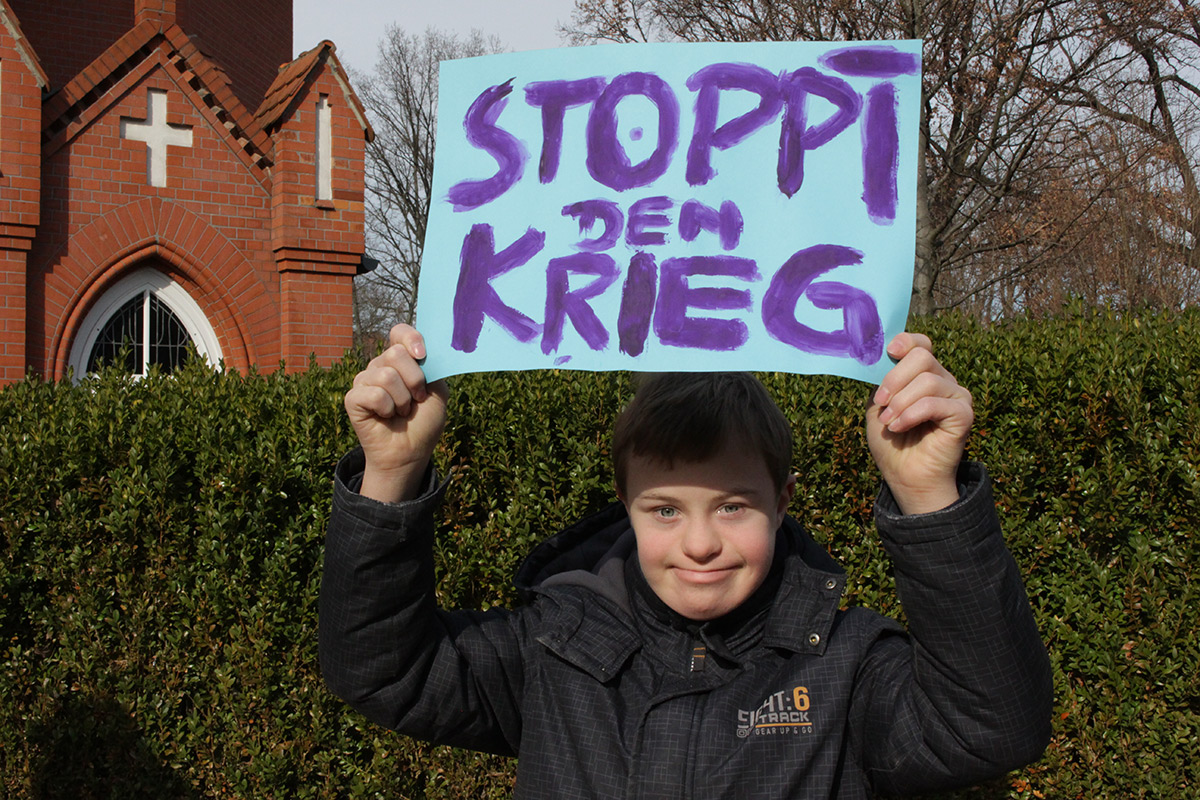 Ein Junge hält ein Schild hoch mit dem er gegen den Krieg in der Ukraine protestiert