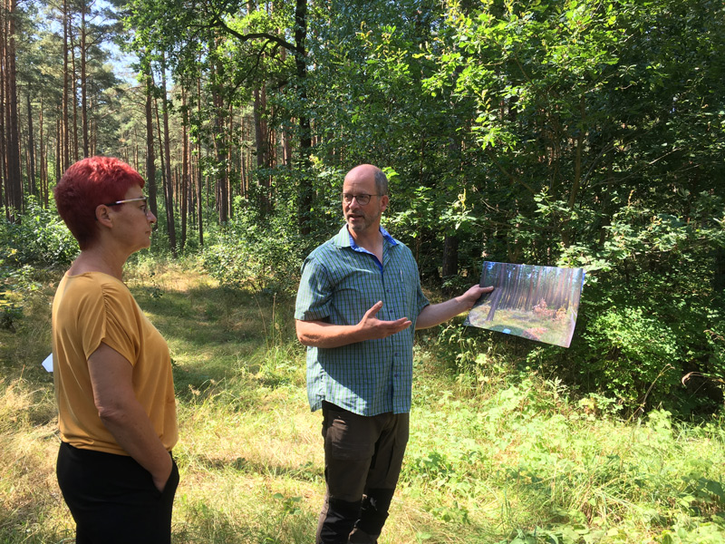Schulförster Joachim Lange zeigt MdL Carla Kniestedt anhand von Fotos den gelungenen Waldumbau im Templiner Stadtforst.