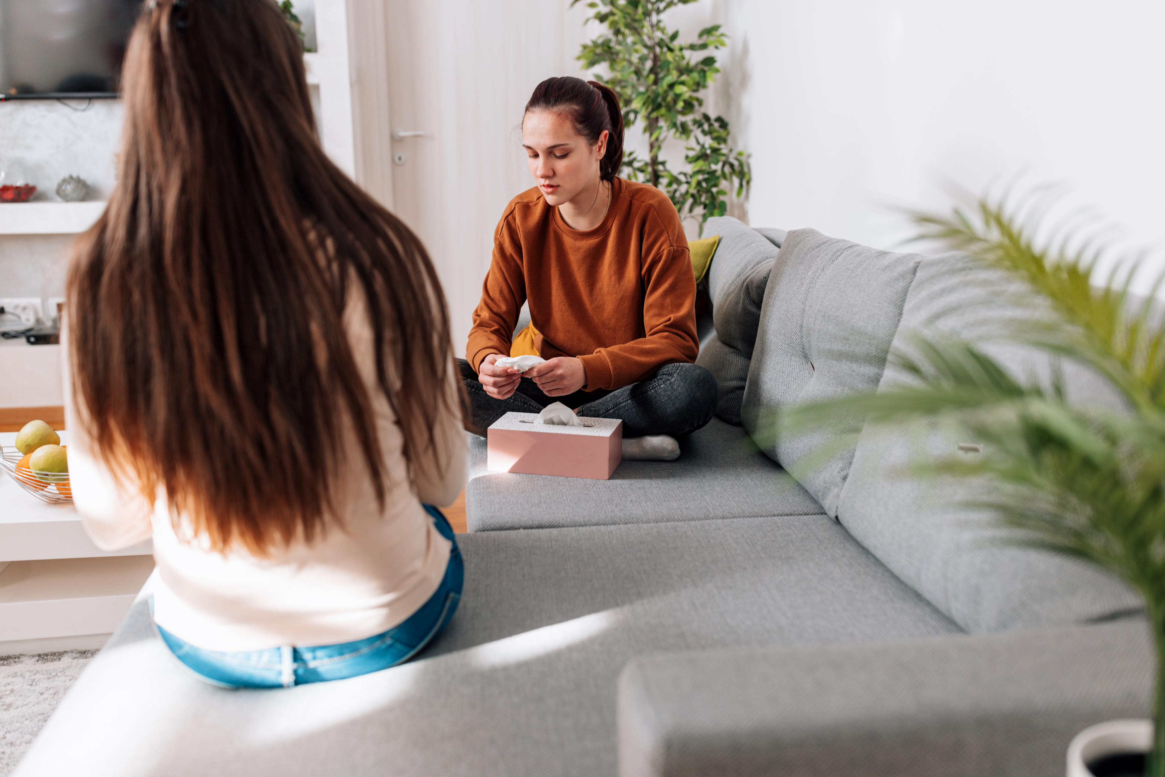 Zwei Frauen sitzen auf einer Couch und unterhalten sich. 