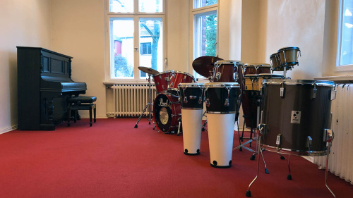 Im Musikraum stehen ein Klavier, mehrere verschieden Schlagzeuginstrumente.