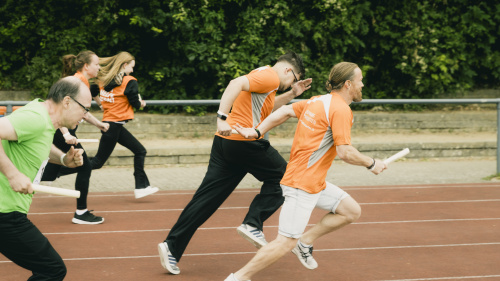 Läufer mit Staffelstab sprinten auf roter Tartanbahn beim Stephanus-Lauf