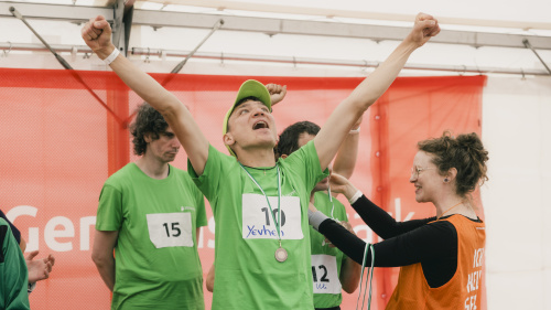 Sportler mit grünem Trikot mit Medaille jubelt mit erhobenen Armen
