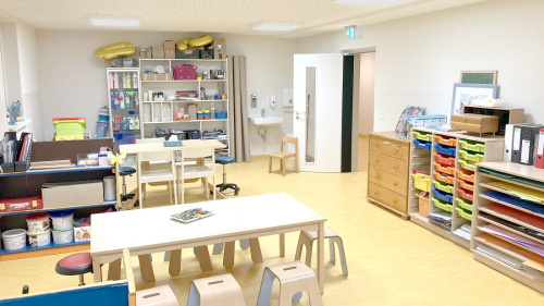 Kleine Tische und Stühle sowie Regale mit buntem Material