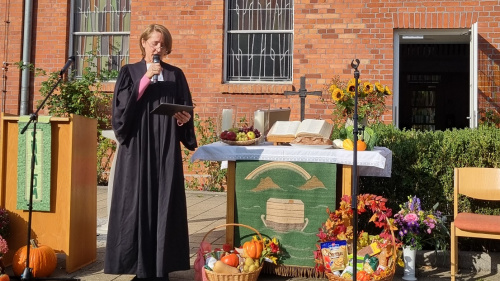 Pastorin steht am Altar vor der Kirche, der mit Obst und Gemüse aus der Ernte geschmückt ist.