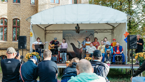 Sommerfest mit Musikgruppe und Publikum vor einer Bühne im Freien.