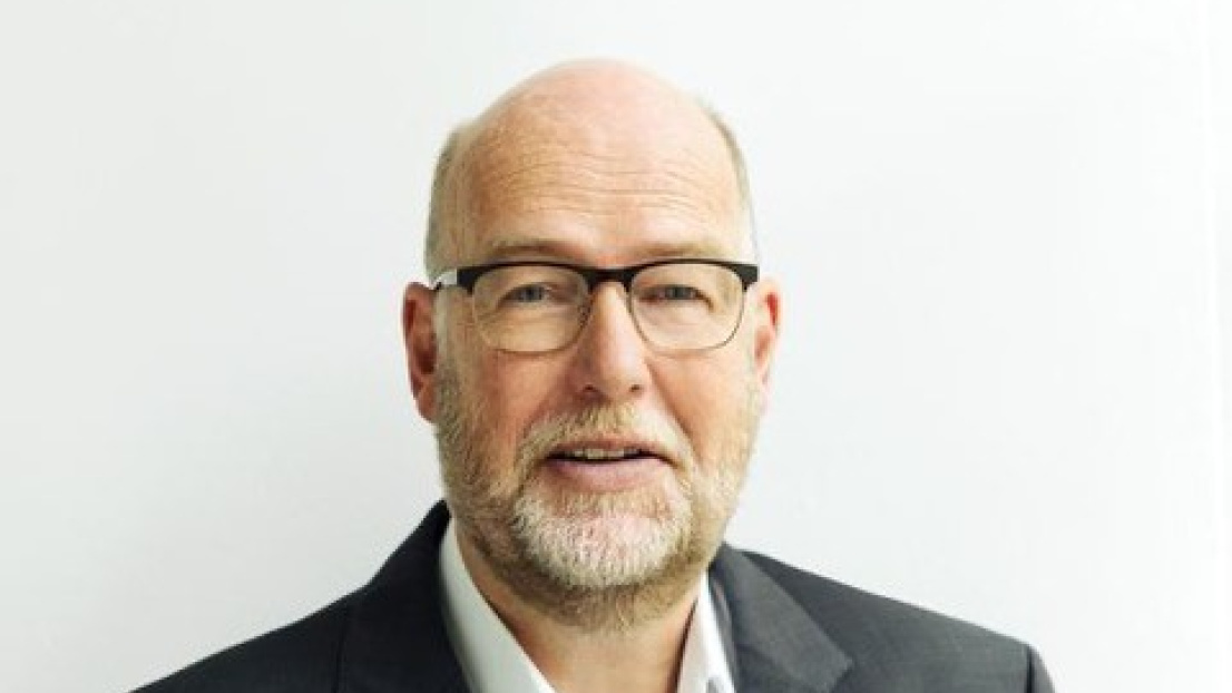 Ein Mann mit Brille schaut freundlich in die Kamera