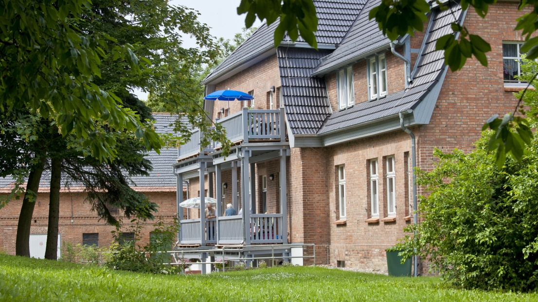 Ein Blick auf ein schönes zweistöckiges Gebäude aus dem roten Backstein mit einer grünen Wiese davor