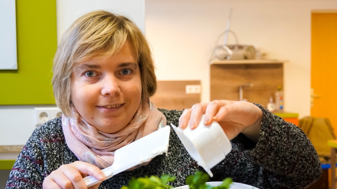 Eine Frau befindet sich in einer Küche und kocht. Sie füllt Quark in eine Rührschüssel.