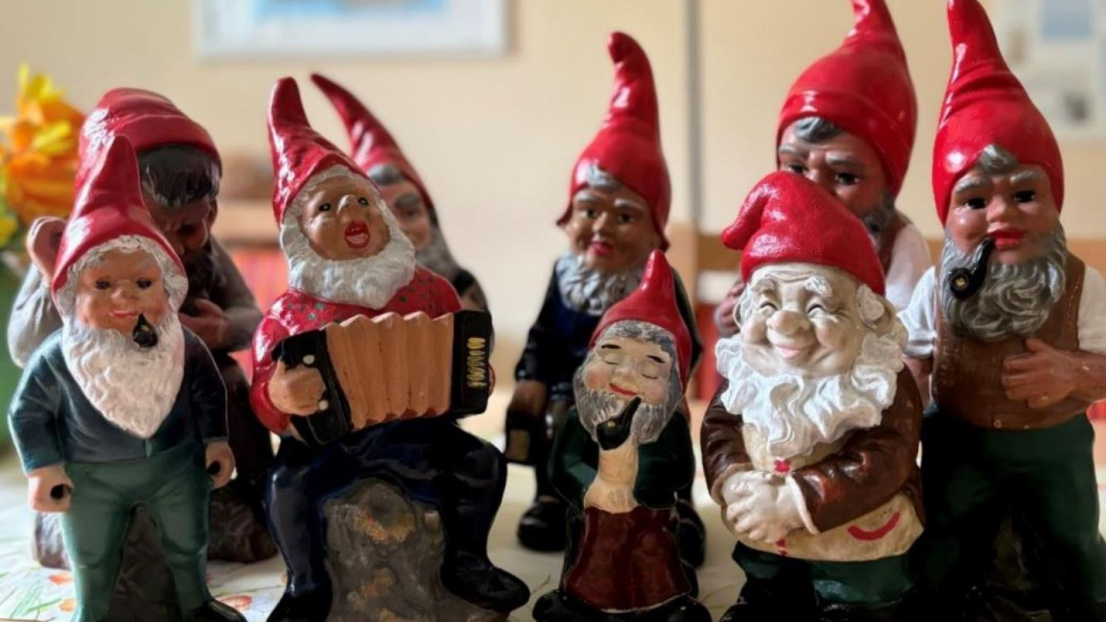 Eine Gruppe fröhlicher Gartenzwerge steht in einem Raum auf dem Tisch