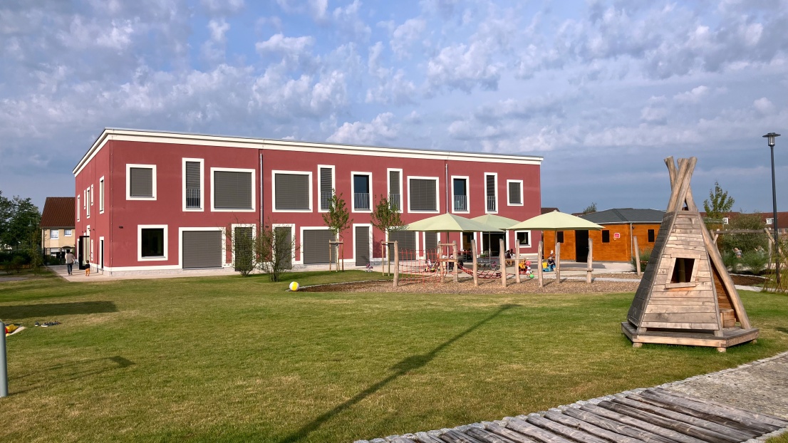 Außenansicht Kita Ahrensfelde mit Teilen des Spielplatz vor dem Haus