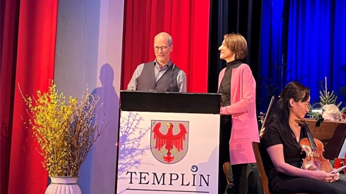 Frau Dr. Ellen Ueberschär, Vorstandsvorsitzende der Stephanus-Stiftung, steht mit einem Mann fröhlich lächelnd an einem Rednerpult auf einer Bühne.