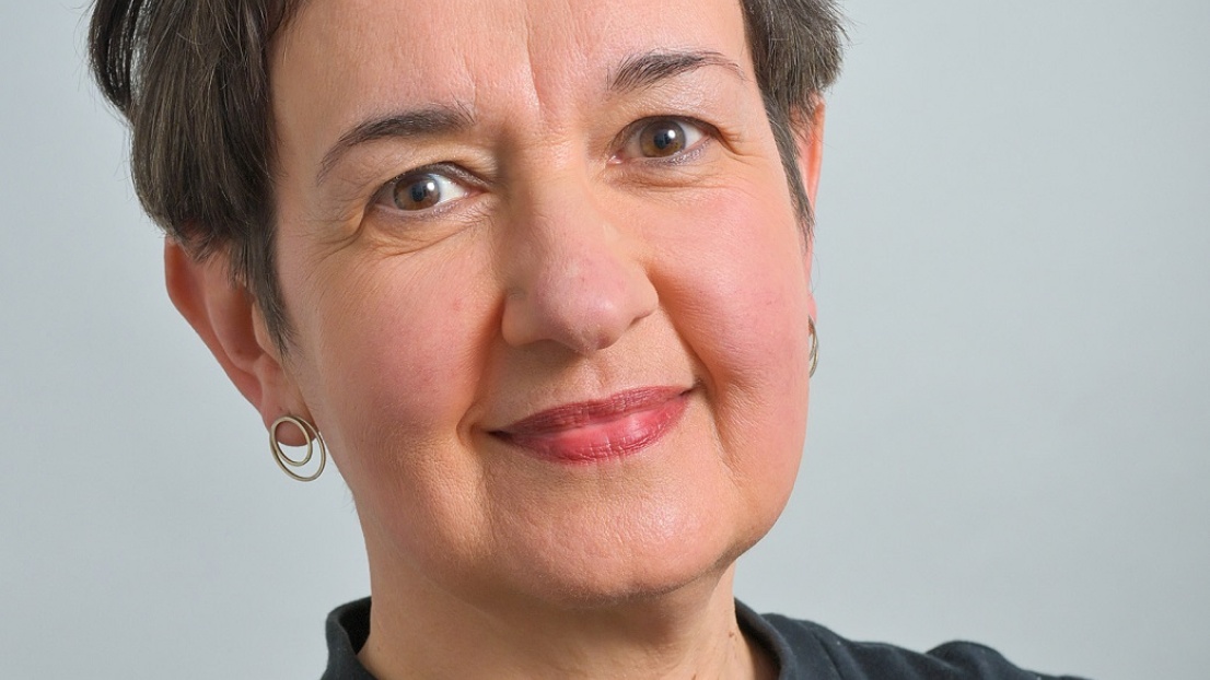 Ein Porträtbild einer Frau mit kurzen Haaren, die in die Kamera lächelt