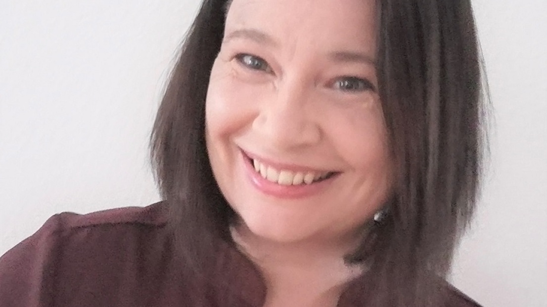 Ein Porträtbild einer Frau mit schulterlangen Haaren, die in die Kamera lächelt
