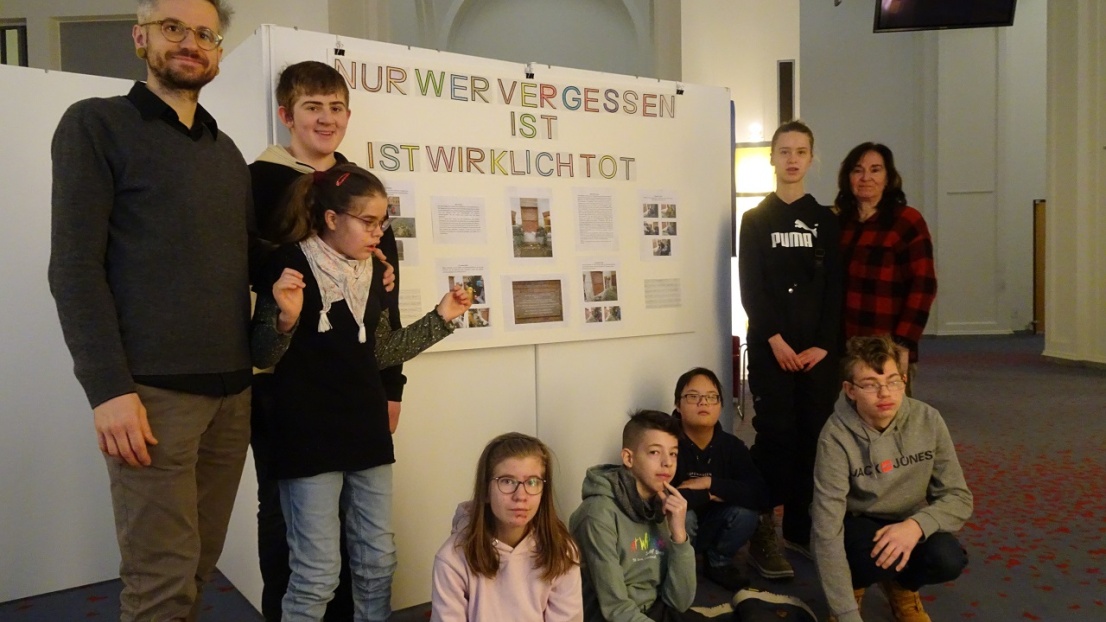 Eine Gruppe Kinder von der Stephanus-Förderschule steht mit zwei Erwachsenen vor einer selbst gestalteten Plakatwand