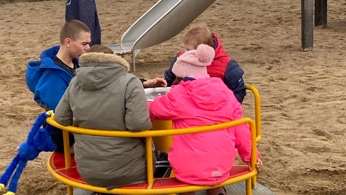 Vier Kinder sitzen auf einem runden Drehkreisel auf einem Spielplatz