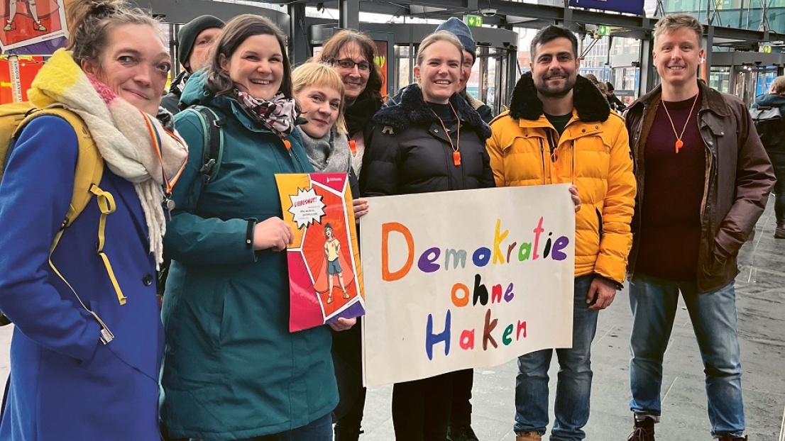 Eine Gruppe von Stephanus-Kolleg*innen steht zusammen und hält lächelnd Plakate in der Hand, z.B. mit der Aufschrift "Demokratie ohne Haken"