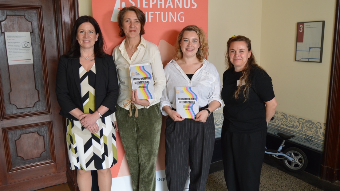 Vier Frauen stehen vor einem Plakat der Stephanus-Stiftung und lächeln in die Kamera