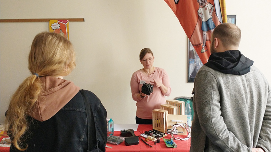 Zwei Menschen stehen vor einem Informationsstand der Stephanus-Stiftung und lassen sich etwas von einer Frau dahinter erklären