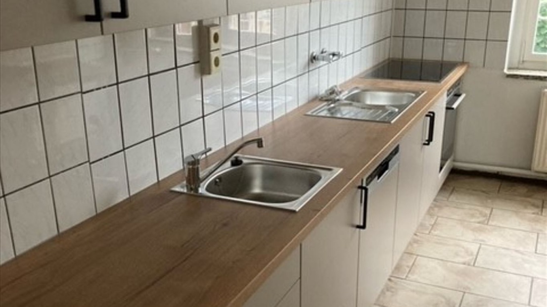 Eine neue Einbauküche mit weißen Schränken und einer holzfarbenen Arbeitsplatte