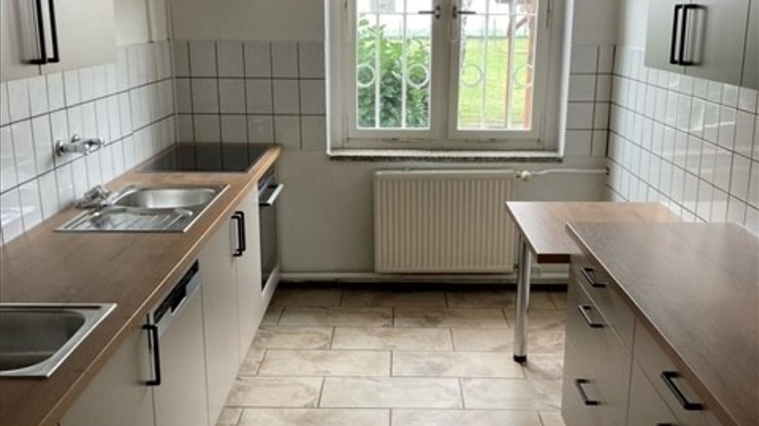 Eine neue Einbauküche mit weißen Schränken und einer holzfarbenen Arbeitsplatte