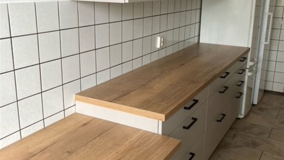 Eine neue Einbauküche mit weißen Schränken und einer holzfarbenen Arbeitsplatte
