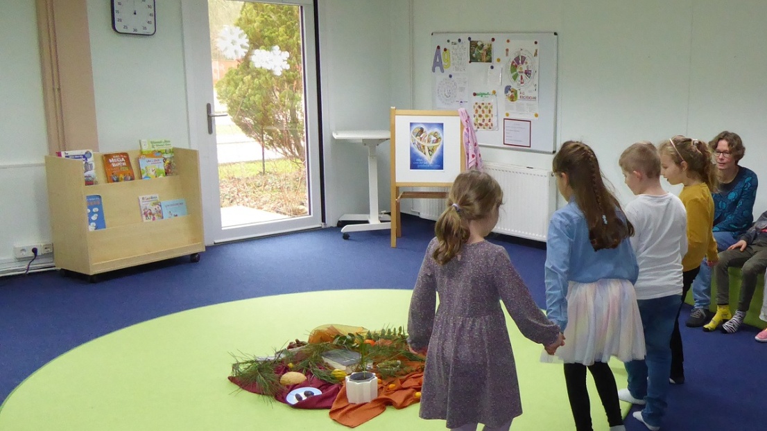 Kinder tanzen um einen geschmückten Kreis in der Mitte des Raums