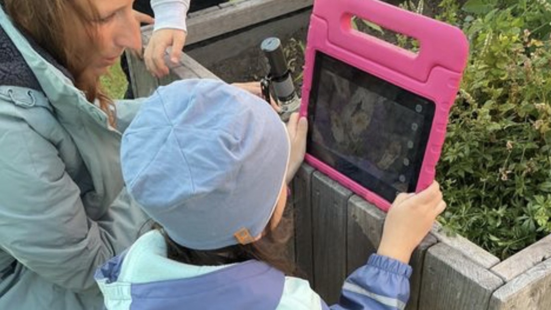 Ein kleines Mädchen und eine Frau schauen zusammen in ein Tablett.