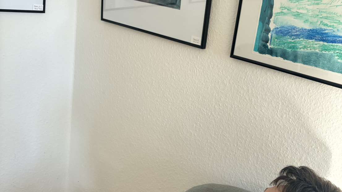 Wine Frau sitzt auf dem Stuhl und schaut nach oben zu den Bildern auf der Wand.