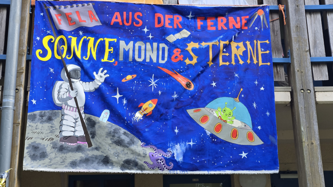 Motto des Sommerferienlagers des Allgemeinen Behindertenverband Brandenburg (ABB) e.V. - Sonne, Mond und Sterne - ein Astronaut auf dem Mond und am Himmel ein Ufo mit einem Alien