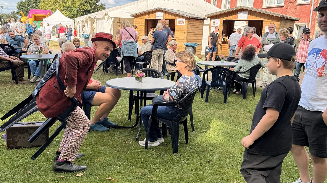 Ein Pantomimekünstler der sich versucht auf einen Stuhl zu setzen