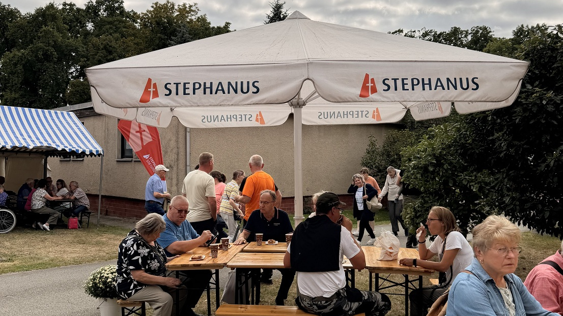 Gäste die essen und unter einem Schirm von Stephanus sitzen