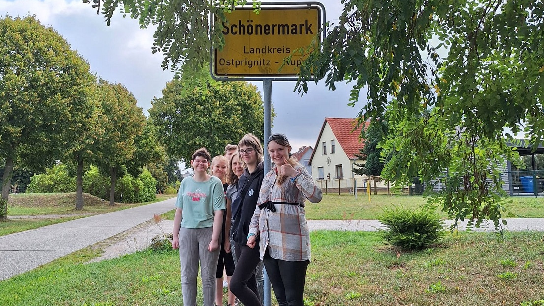 Eine Gruppe von jungen Frauen steht am Ortsschild Schönermark