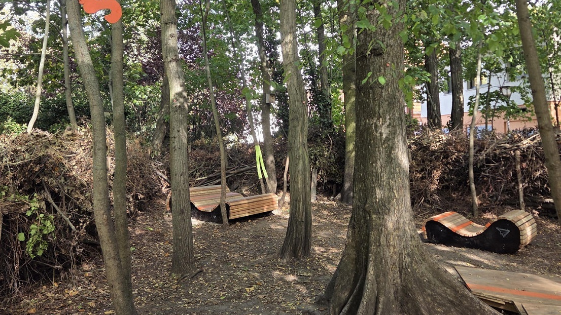 Zwei Holzgartenliegen stehen im Wald. Auf einem Baum ist ein Eichhörnchen aus Holz.