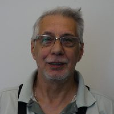 Ein Mann mit Brillen und grauen Haaren schaut fröhlich in die Kamera