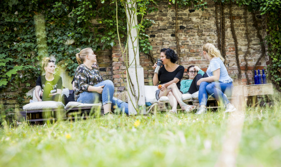 Vier Junge frauen sitzen auf Bänken im Garten des Oberlin-Seminars und erzählen miteinander.