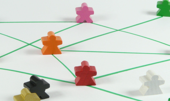 Mit Stift gezeichnete grüne Wege auf Papier, verbunden durch bunte Spielfiguren zwischen den Pfaden