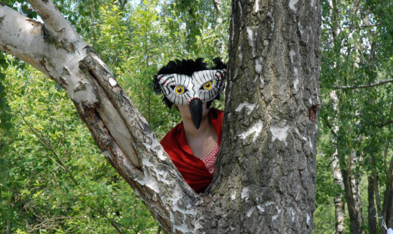 Person mit selbstgebauter Maske zwischen Bäumen
