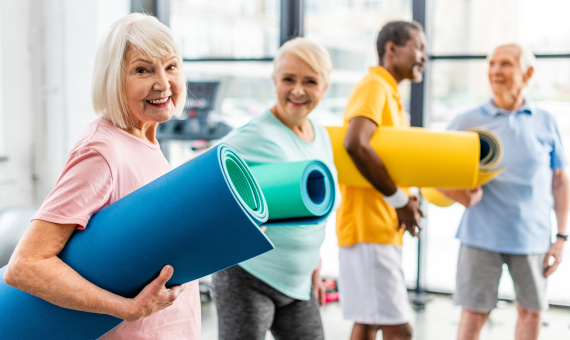Seniorinnen und Senioren mit Gymnastikmatten in einem Bewegungsangebot.