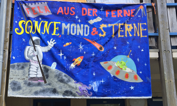 Motto des Sommerferienlagers des Allgemeinen Behindertenverband Brandenburg (ABB) e.V. - Sonne, Mond und Sterne - ein Astronaut auf dem Mond und am Himmel ein Ufo mit einem Alien