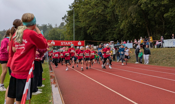 Viele Schülerinnern und Schüler starten bei einem Lauf. Sie rennen, im Hintergrund hängt das Start-Banner.