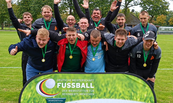 12 Männer in Sportbekleidung tragen stolz ihre Medaillen und stehen zusammen vor einem Fußball-Banner